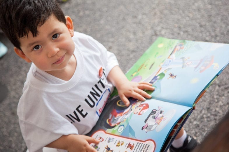 Boy wearing a United Way shirt while reading a book.