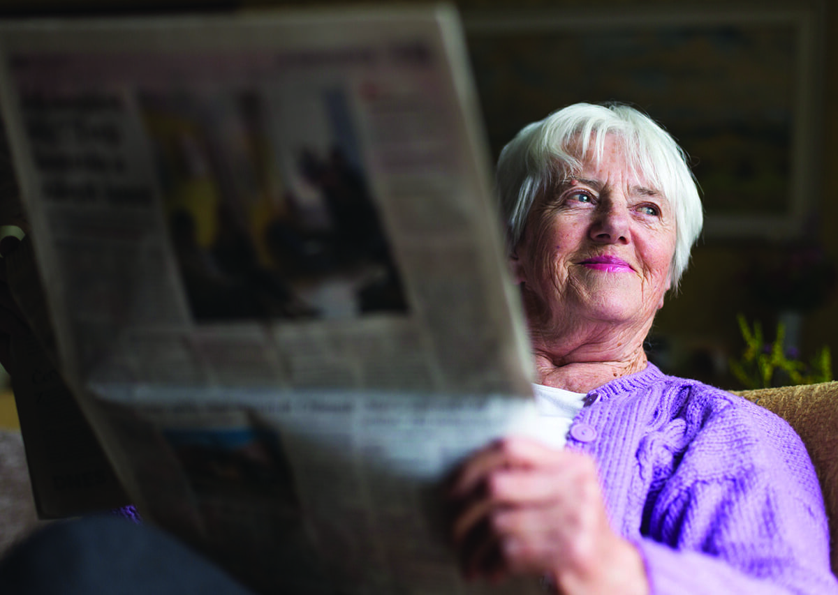 Senior woman reading morning newspaper, sitting in her favorite