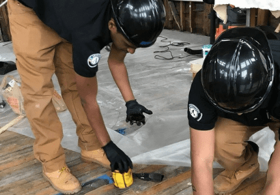 Two Youthbuild Preparatory Academy students sealing a wooden floor. Youthbuild is one of many organizations that make up Rhode Island's nonprofit sector. YOUTHBUILD PREPARATORY ACADEMY