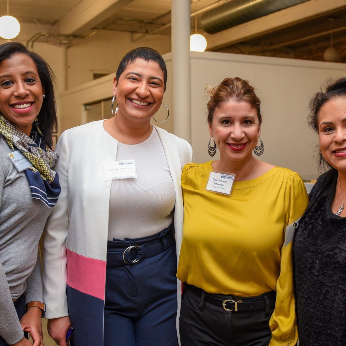 Four smiling Women United members, including (from left to right) Stephanie Pelletier, Ashley Sanchez, and Paola Fonseca-Fernandez.