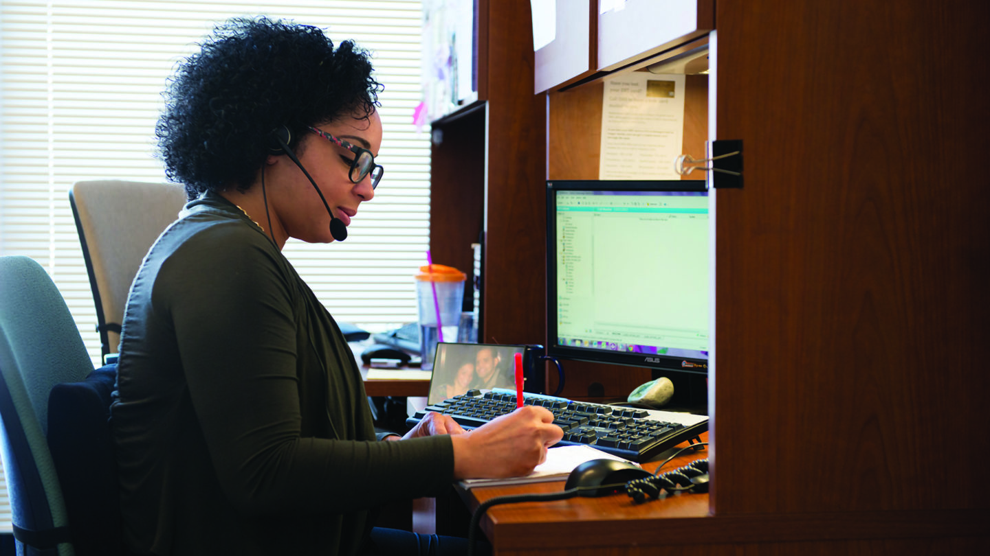 Evelyn Cabrera, senior bilingual community resource specialist for 211, writes notes at her desk.