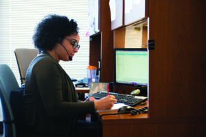 Evelyn Cabrera, senior bilingual community resource specialist for 211, writes notes at her desk.