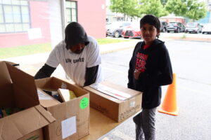 A volunteer poses next to boxes of books.