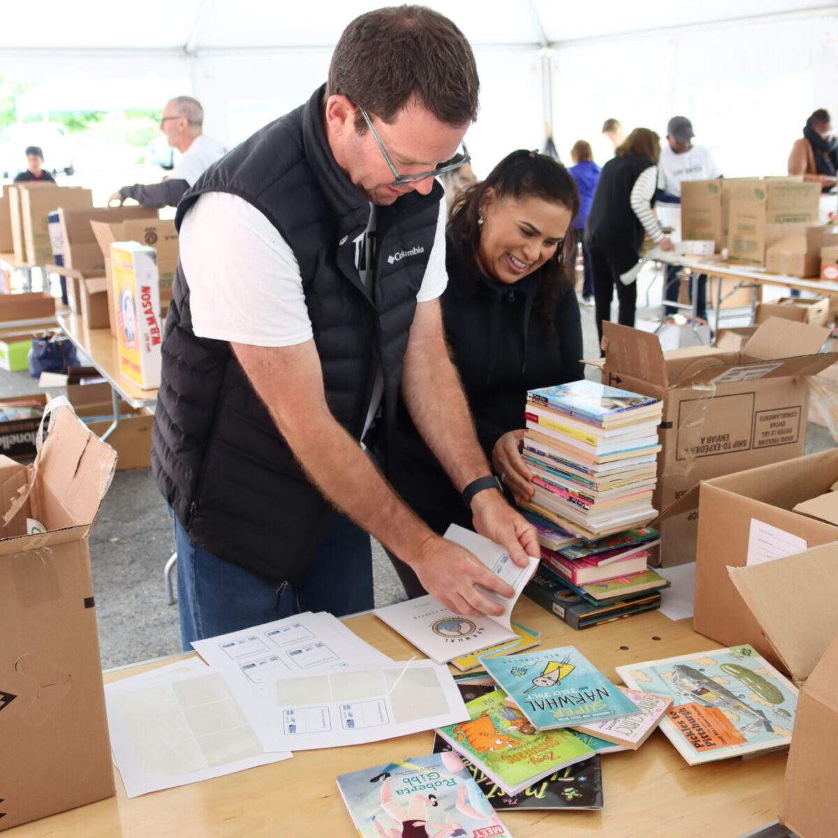 David Nicolato, husband of Cortney Nicolato, labels books with Women United member Sandra Mazo.