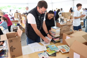 David Nicolato, husband of Cortney Nicolato, labels books with Women United member Sandra Mazo.