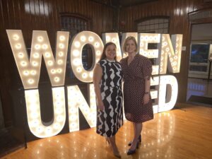United Way of Rhode Island’s Karen Alzate and Cortney Nicolato pose in front of marquee letters.