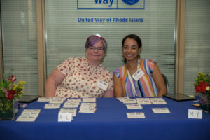 Marlene Guay and Rosilia Guerra pose behind a table with name tags.