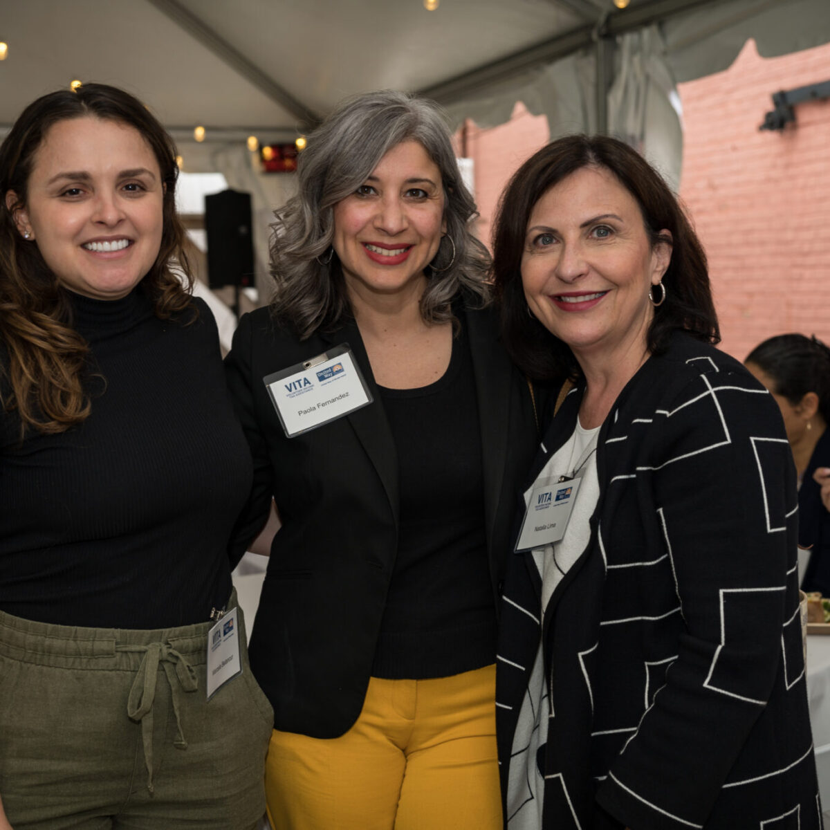 Marcela Betancur, Paola Fernandez, and Natalia Lima pose under a tent.