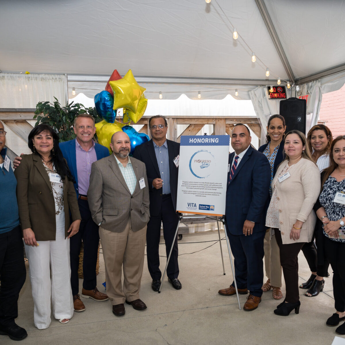 Progreso Latino staff and supporters pose next to a sign announcing their award.