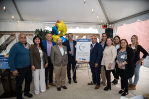 Progreso Latino staff and supporters pose next to a sign announcing their award.