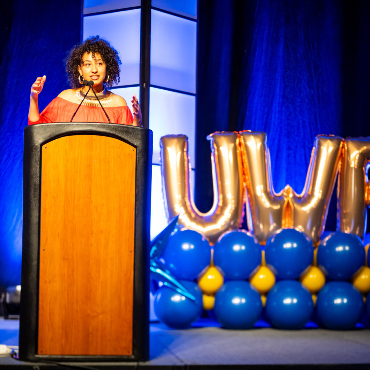 Lexus Fernandez, American motivational speaker and co-founder of Soulita, speaks from a podium.