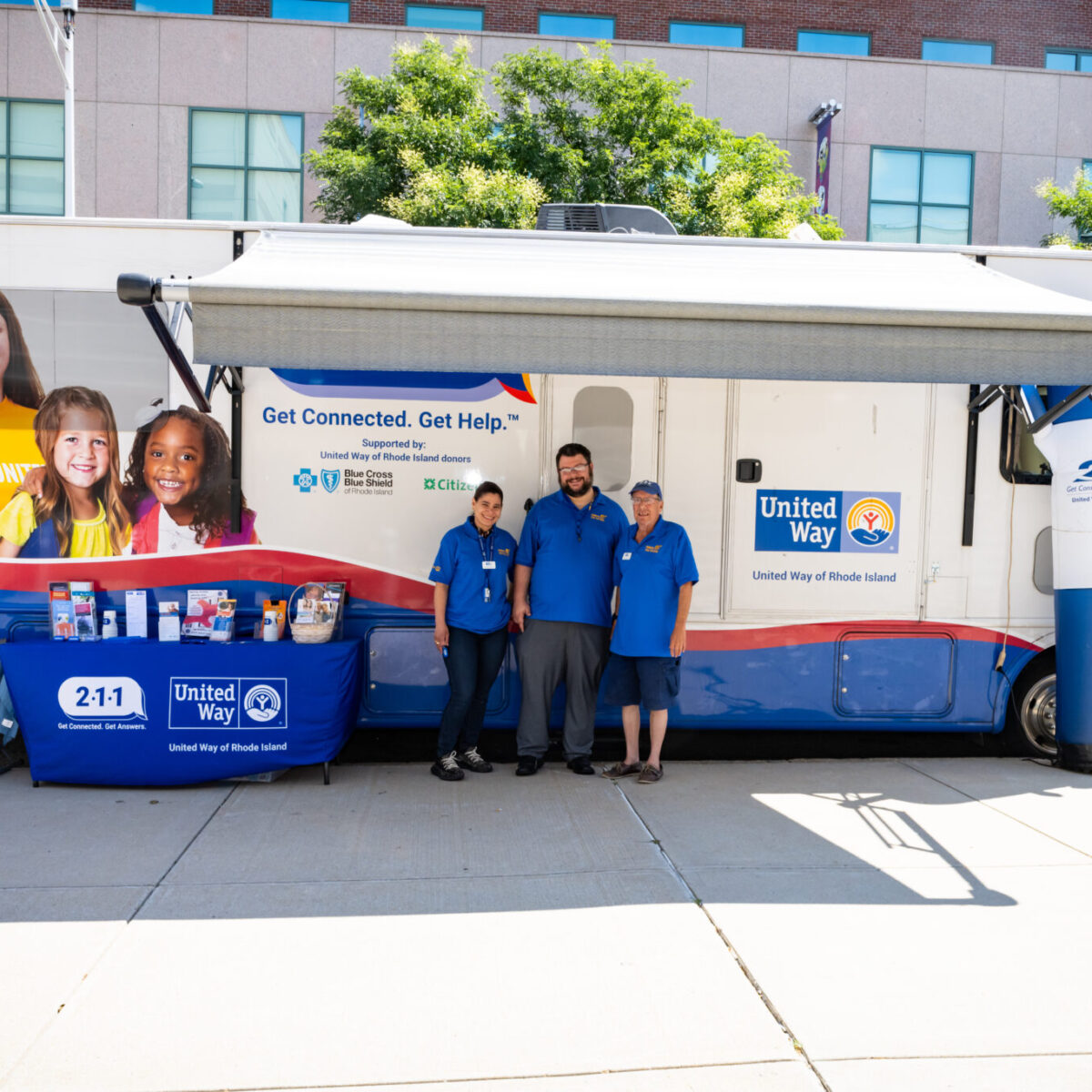 United Way 211 in Rhode Island staff standing in front of the 211 recreational vehicle (RV).