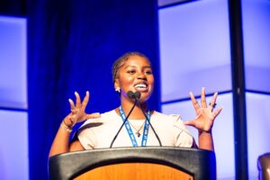 Zainabou Thiam, CEO of Sunu Body and co founder and president of Silence is Violence: 401, speaking from a podium.