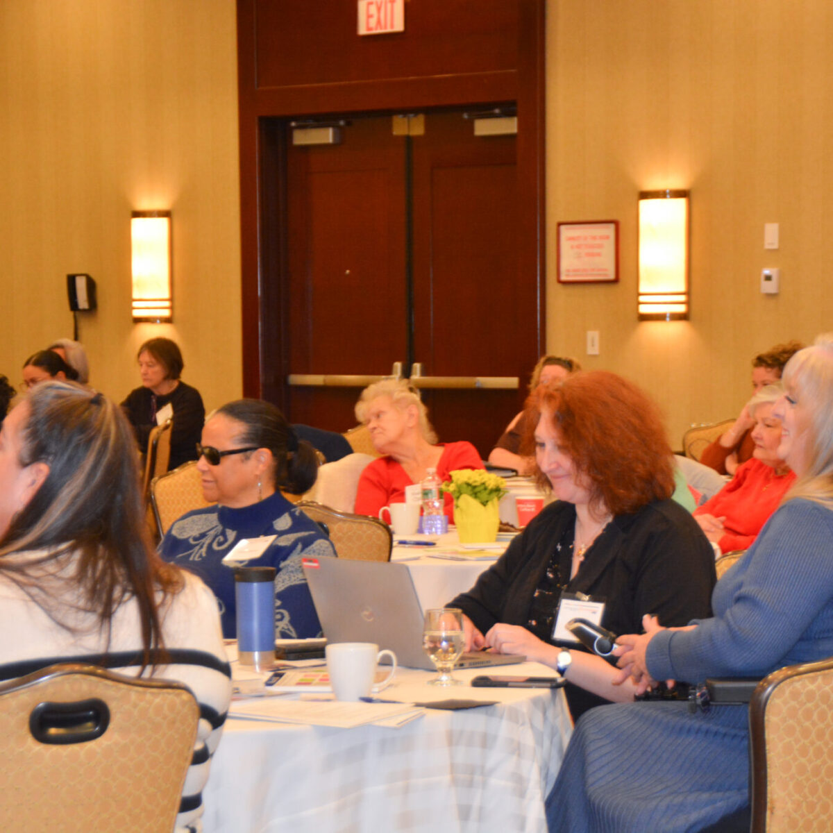 Conference attendees Maria Cimini and Tina Guenette Pedersen smiling as other attendees look on.