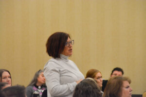 Conference attendee asking a question as other attendees look on.