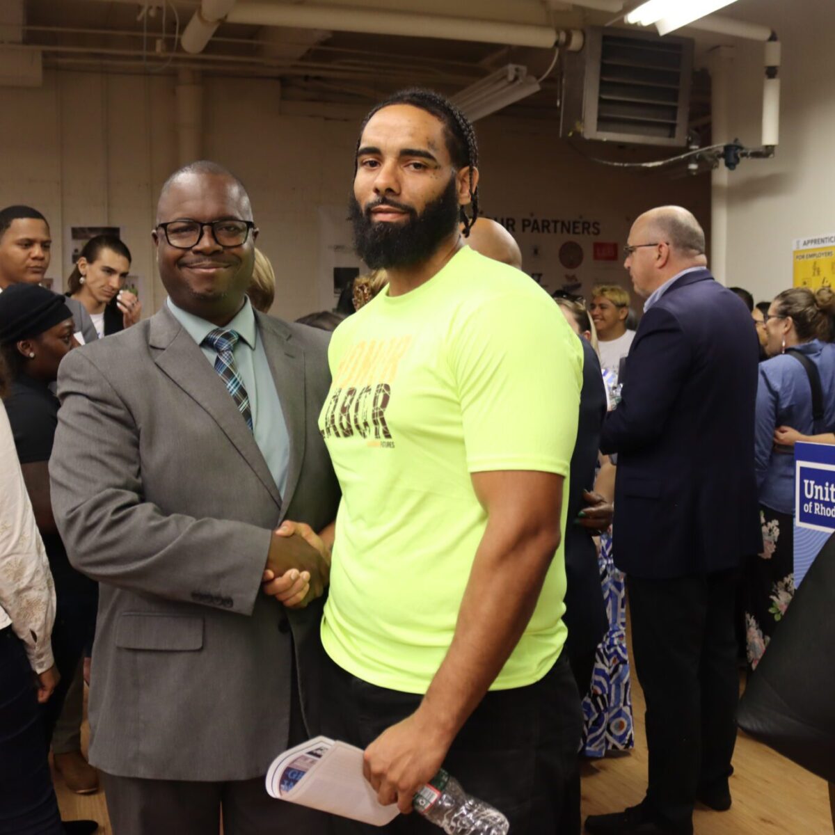 Larry Warner, DrPH, chief impact and equity officer for United Way of Rhode Island, shaking hands with another Black man.