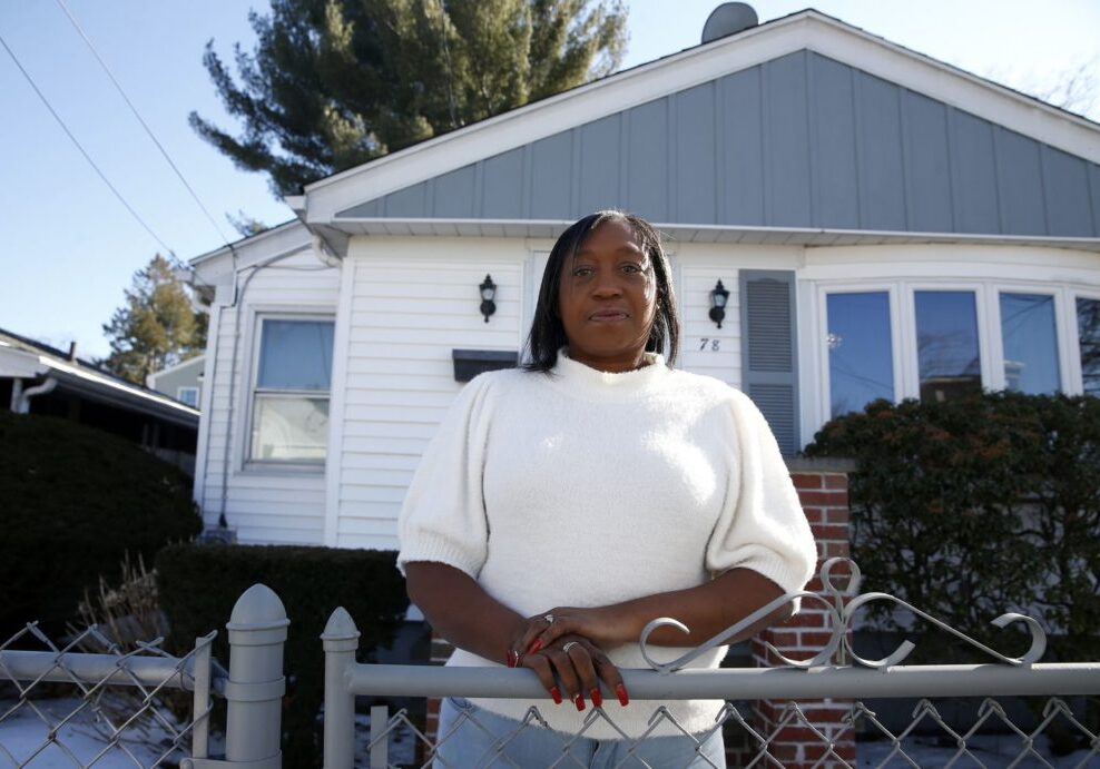 Diana Garlington standing at a fence in front of her home. By JONATHAN WIGGS/GLOBE STAFF